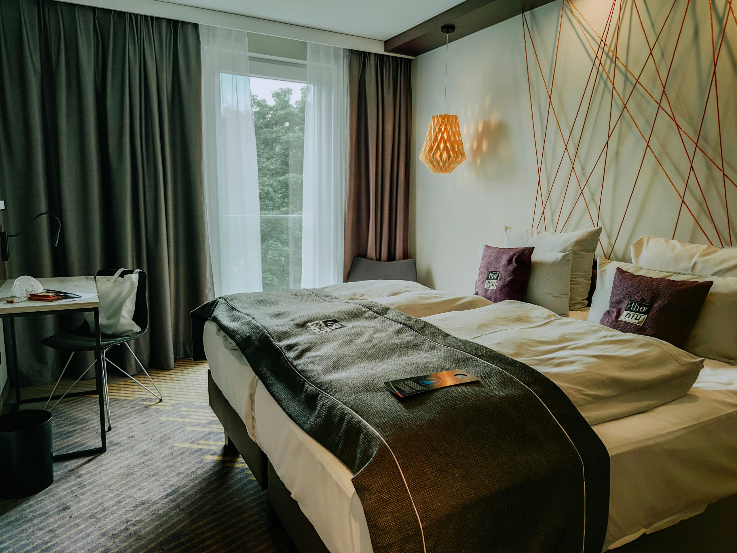 A modern and cozy hotel room featuring a double bed, stylish lighting, and a workspace.