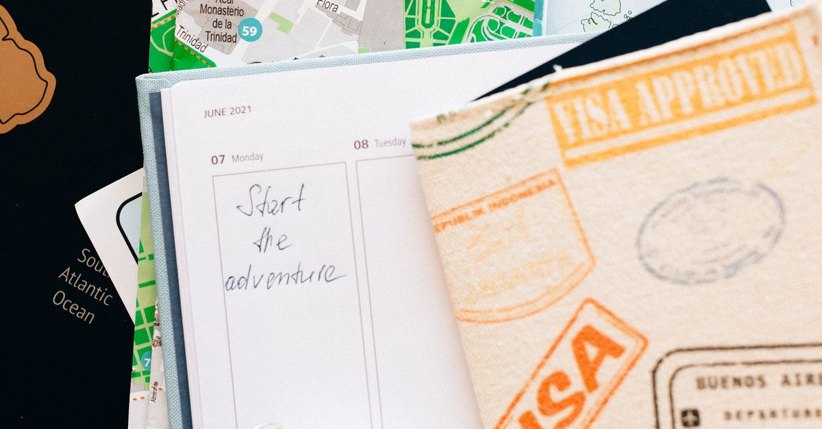 Flat lay of travel essentials including compass, notebook, and map for a journey.